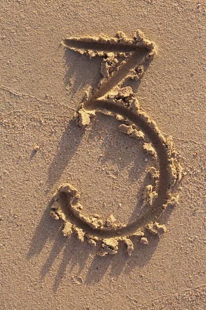 Number three written on a sandy beach. Handwritten characters collection.