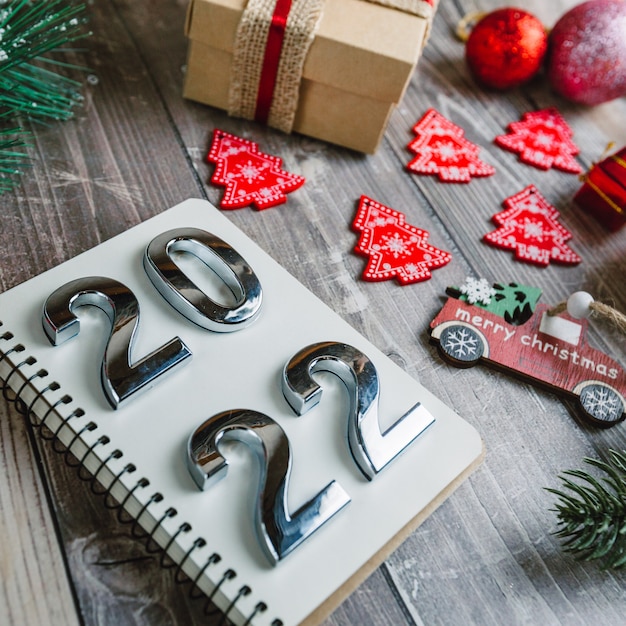 Photo numbers 2022 on a spiral notepad on a wooden background with christmas decorations