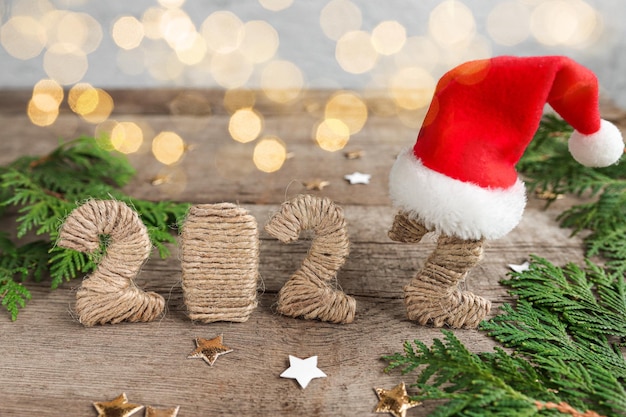 Numbers 2022 on a wooden table with Christmas decorations and red santa hat front view