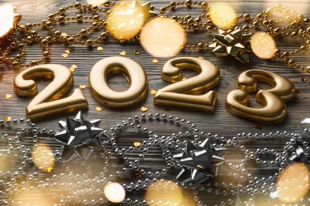 Photo numbers 2023 closeup on a wooden background with christmas decorations and garland lights