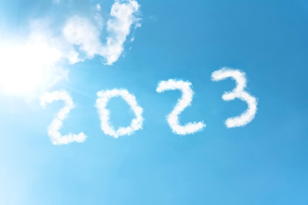 写真 明るい太陽に照らされた雲の白い煙からの青空の背景に数字 2023 シンボルの碑文