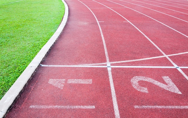 赤いランニングトラックランニングトラックと緑の芝生の番号の開始点ダイレクトアスレチックスポーツスタジアムのランニングトラック