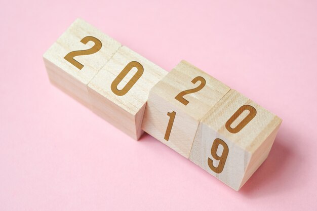 Numbers on wooden cubes on pink background.