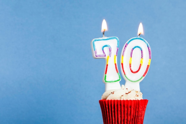 Nummer 70 verjaardagskaars in een cupcake tegen een blauwe achtergrond