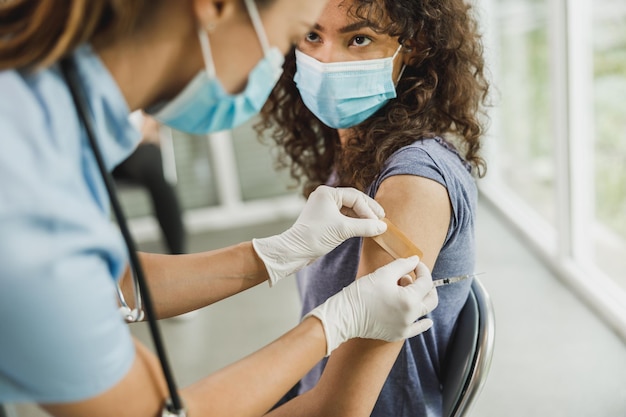 A nurse applying a band aid to an African American girl after receiving a vaccine due to coronavirus epidemic.