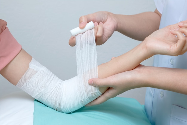 Photo nurse applying bandage to patient injured elbow