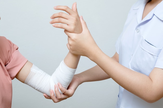 Nurse applying bandage to patient injured elbow