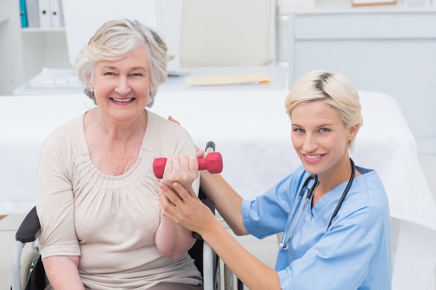 Nurse assisting female patient in lifting dumbbell