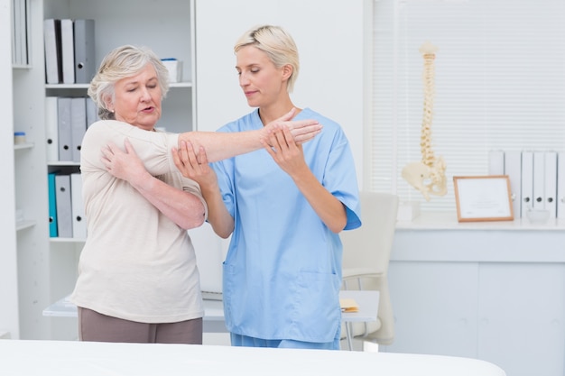 Nurse assisting senior patient in raising arm