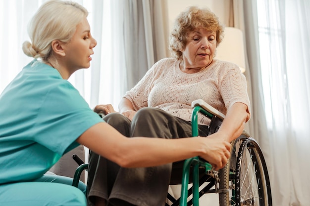 Nurse assisting senior woman using wheelchair in nursing home