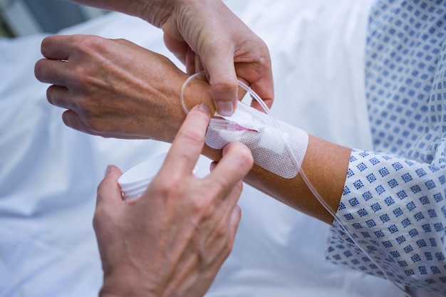 Nurse attaching iv drip on patient s hand