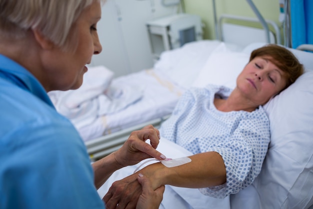 Photo nurse attaching iv drip on patients hand