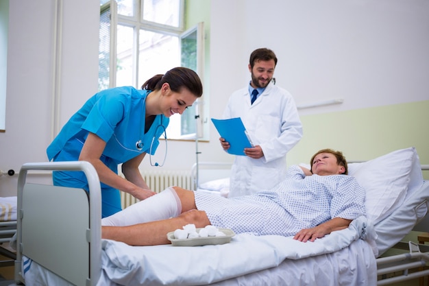 Nurse bandaging leg of patient