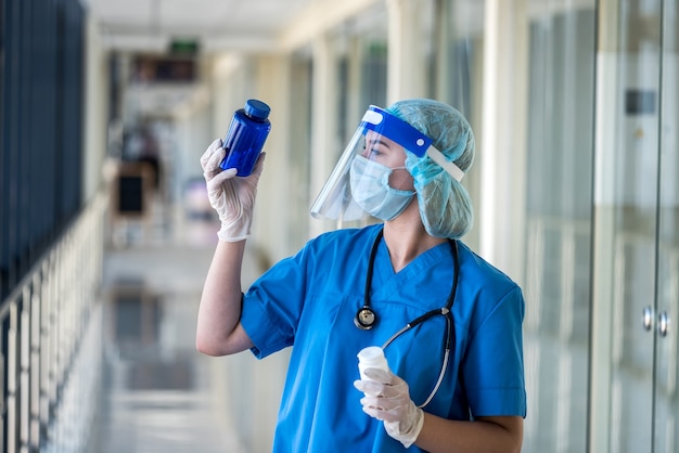 白い錠剤とボトルを保持している青い制服を着た看護師。医療の概念