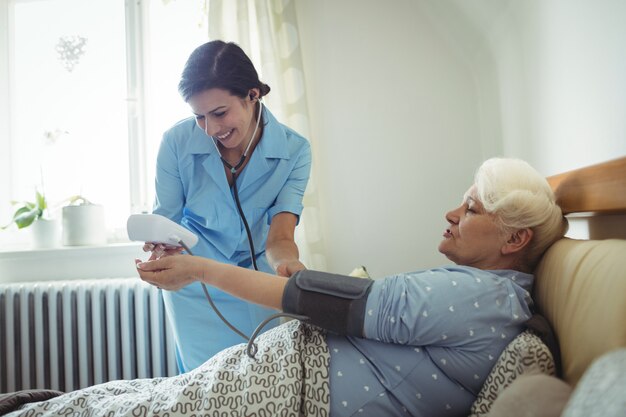 Nurse checking blood pressure of senior woman