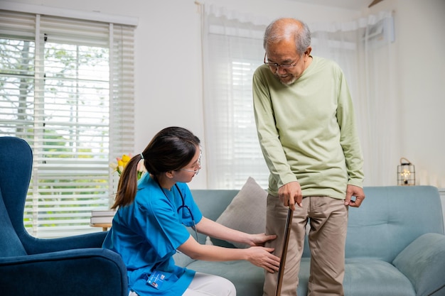 膝の痛みに苦しむ年配の老人患者の手術後に膝と脚をチェックする看護師
