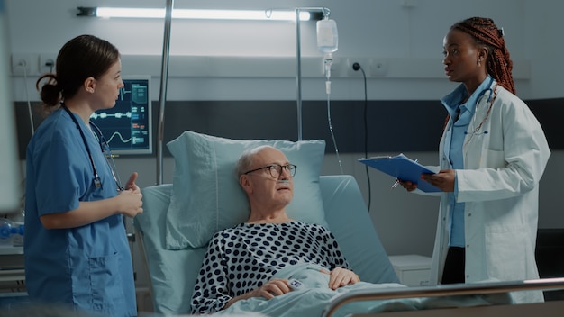 Nurse checking oximeter on sick patient in hospital ward