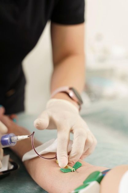 Nurse collecting patients blood sample for test or donation in medical clinic