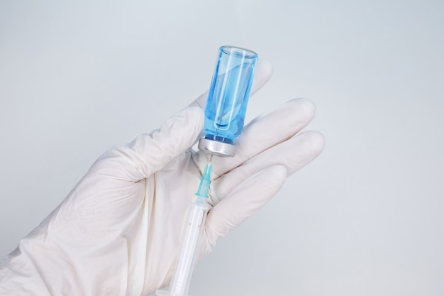 Nurse collects medicine from an ampoule into a syringe in white sterile gloves. Healthcare cure concept. Coronavirus, Covid 19 virus, vaccine vial