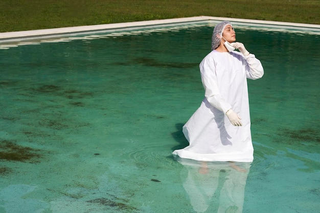 Nurse cools off in pool water in summer nurse wearing protective suit walking in swimming pool
