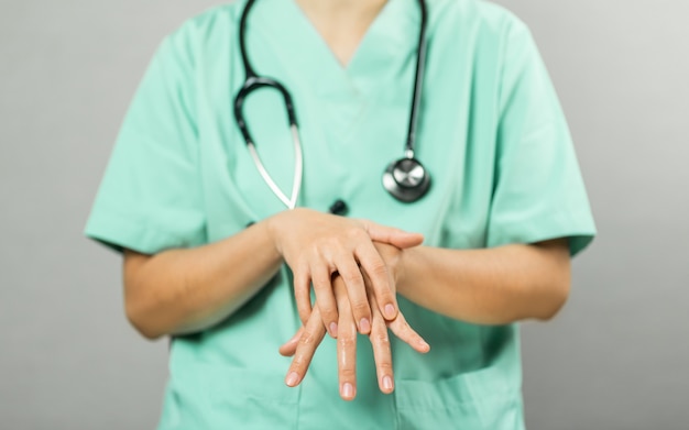 緑の服と聴診器の看護師または医師は、コロナウイルスまたはcovid-19の保護のための洗浄とクリーニングを実証しています