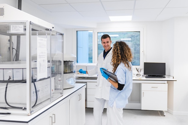 Photo a nurse and a doctor smile as they review data together in a bright hospital laboratory