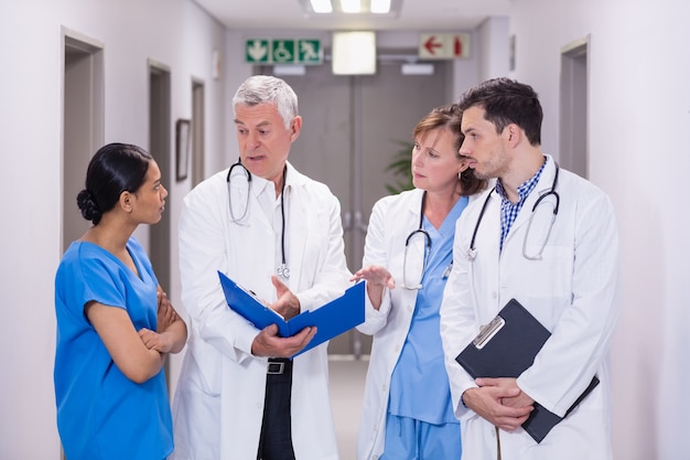 Nurse and doctors discussing over clipboard