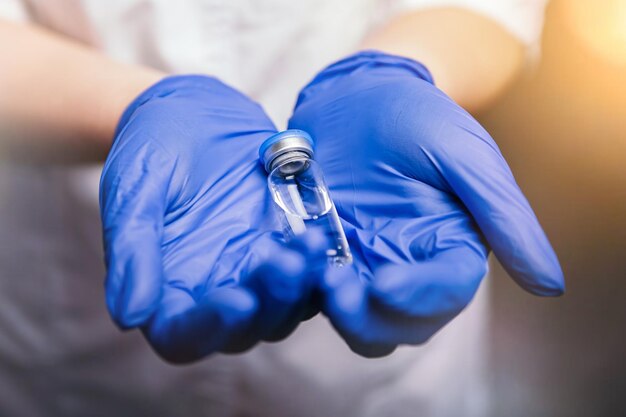 Nurse dressed in medical gown hold bottle with vaccine