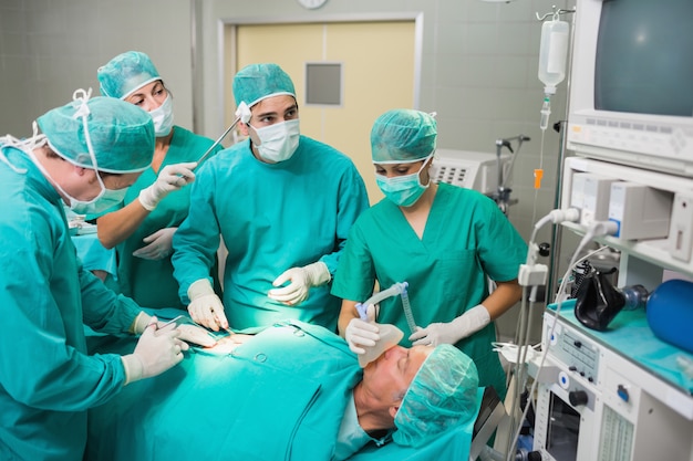 Nurse drying forehead of a surgeon next to a patient