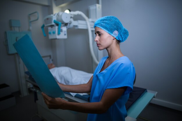 Nurse examining medical report in x-ray room