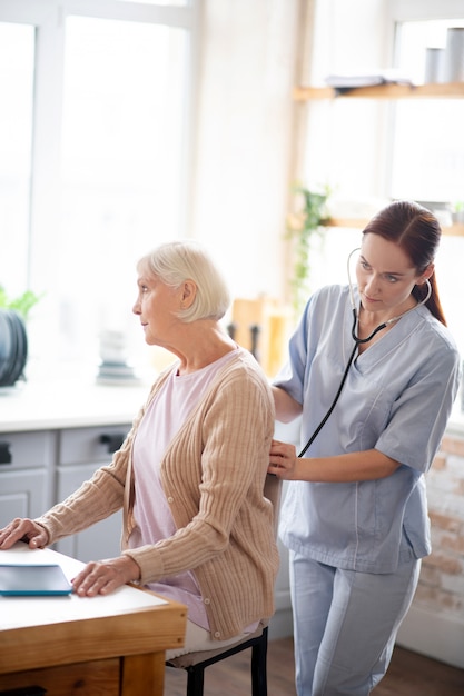 Nurse examining retired lady feeling sick and tired