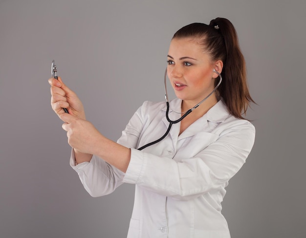 Nurse in gauze is against grey background with black stethoscope