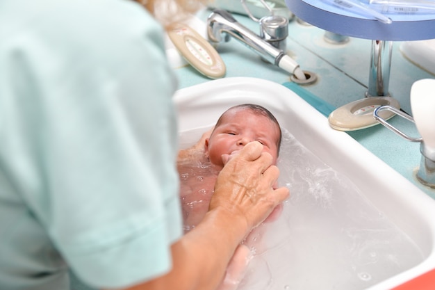 A nurse gives the first bath of a newborn baby