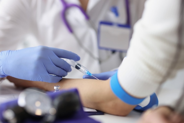 Nurse giving intravenous injection into patient ulnar vein at clinic closeup