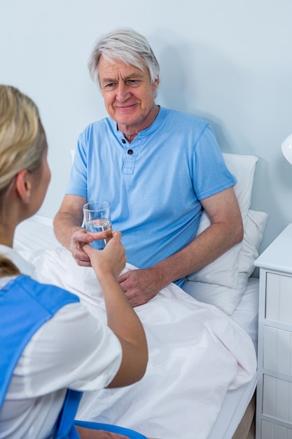 Nurse giving medicins to senior man at home