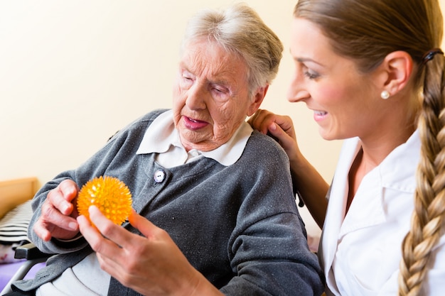 Foto infermiera che dà terapia fisica alla donna senior