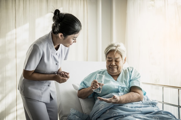 Nurse giving senior woman medical pills.