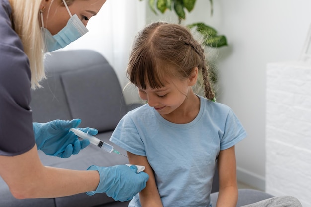 nurse giving vaccination injection to little girl patient.