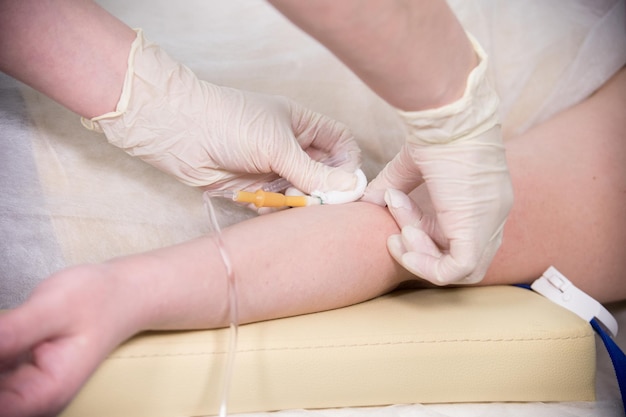 Медсестра в перчатках берет образец крови из руки для тестирования