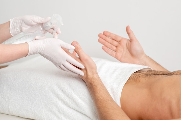 Nurse hand sanitizing hands of male patient in the hospital. Coronavirus protection concept.