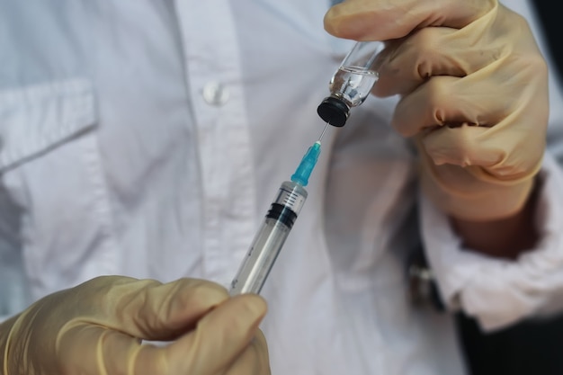 Nurse hands holding syringe and ampoule