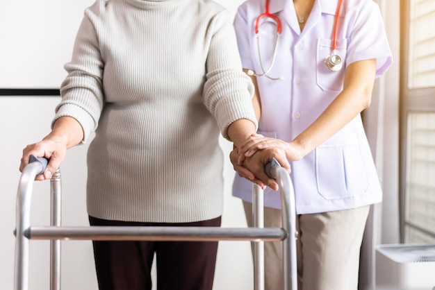 Nurse helping senior woman hand holding walker trying to walk,Care nursing home concept