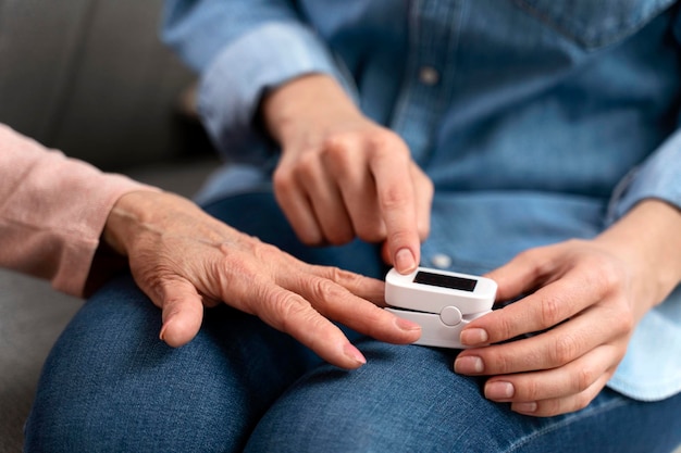 Nurse helping to senior woman using blood sugar test on finger in living room Health innovation and daily life of diabetic lady with glucometer to check glucose level in her home