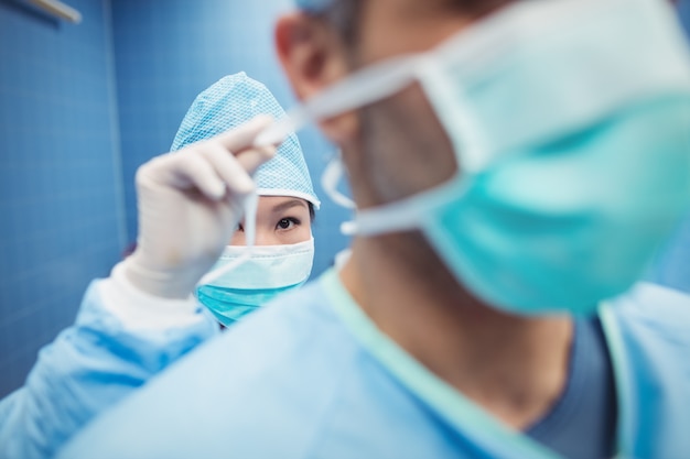 Nurse helping a surgeon in tying surgical mask