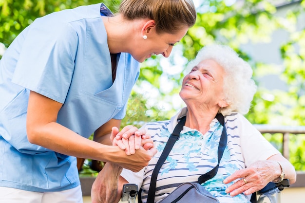 Photo nurse helping woman sitting against trees