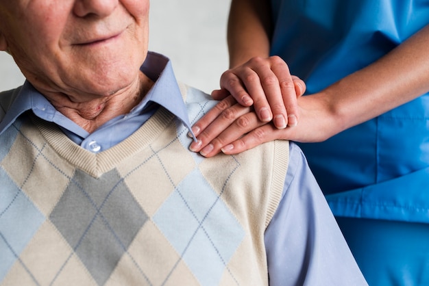 Photo nurse holding old man's shoulder close-up