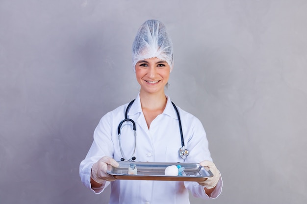 Nurse holding tray with medicines on gray background. Doctors on gray background. Vaccine and medication. Concept of health and care