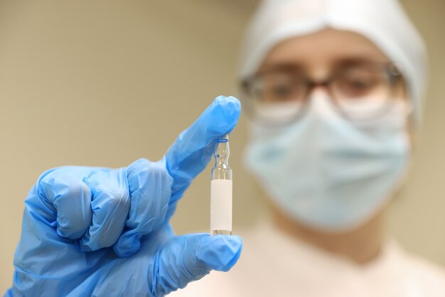 A nurse holds an ampoule with a vaccine in her hands