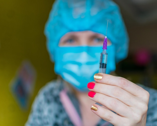 A nurse holds an elongated hand with a syringe