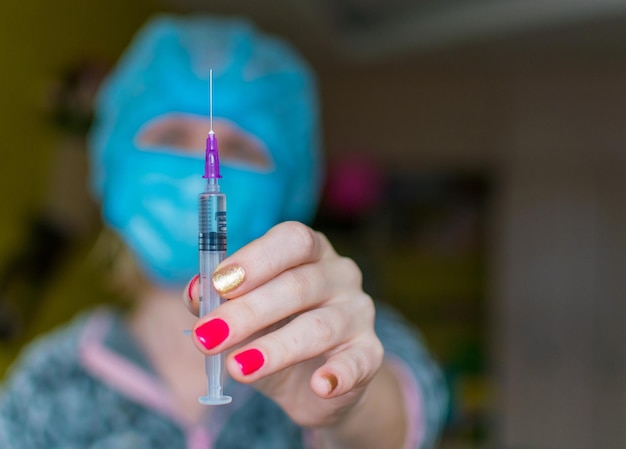 A nurse holds an elongated hand with a syringe